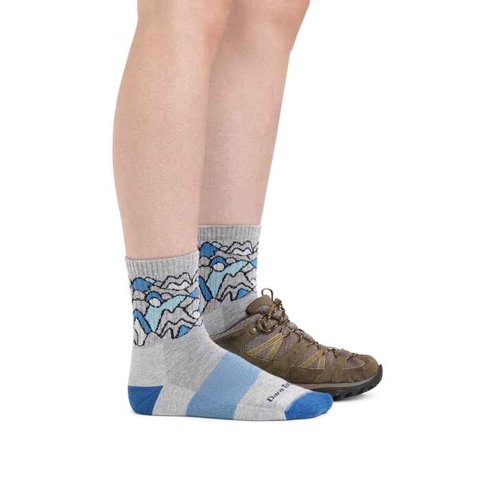 Profile image of a woman's legs on a white background, facing to the right, wearing Women's Coolmax Overlook Micro Crew Midweight Hiking Socks in Light Gray with a hiking boot also on the foot in back
