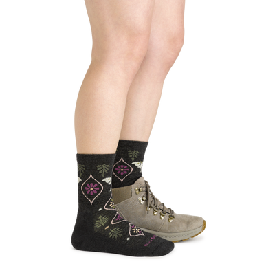 Side studio shot of model wearing women's luna micro crew hiking sock in charcoal with light brown hiking shoe on left foot
