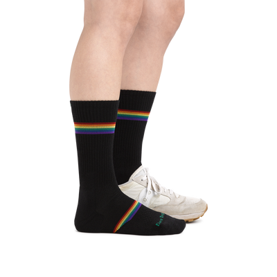 Profile image of a woman's legs on a white background wearing Women's Prism Crew Lightweight Athletic Socks in Black with one foot also in an athletic shoe