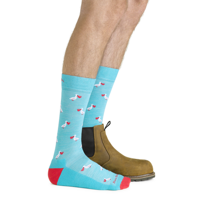 Side shot of model wearing the men's pelican crew lifestyle sock in aqua with a brown boot on his left foot