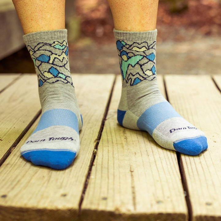 Close up photo of a woman standing on a wooden walkway, barefoot, wearing Women's Coolmax Overlook Micro Crew Midweight Hiking Socks in Light Gray, Lifestyle Image