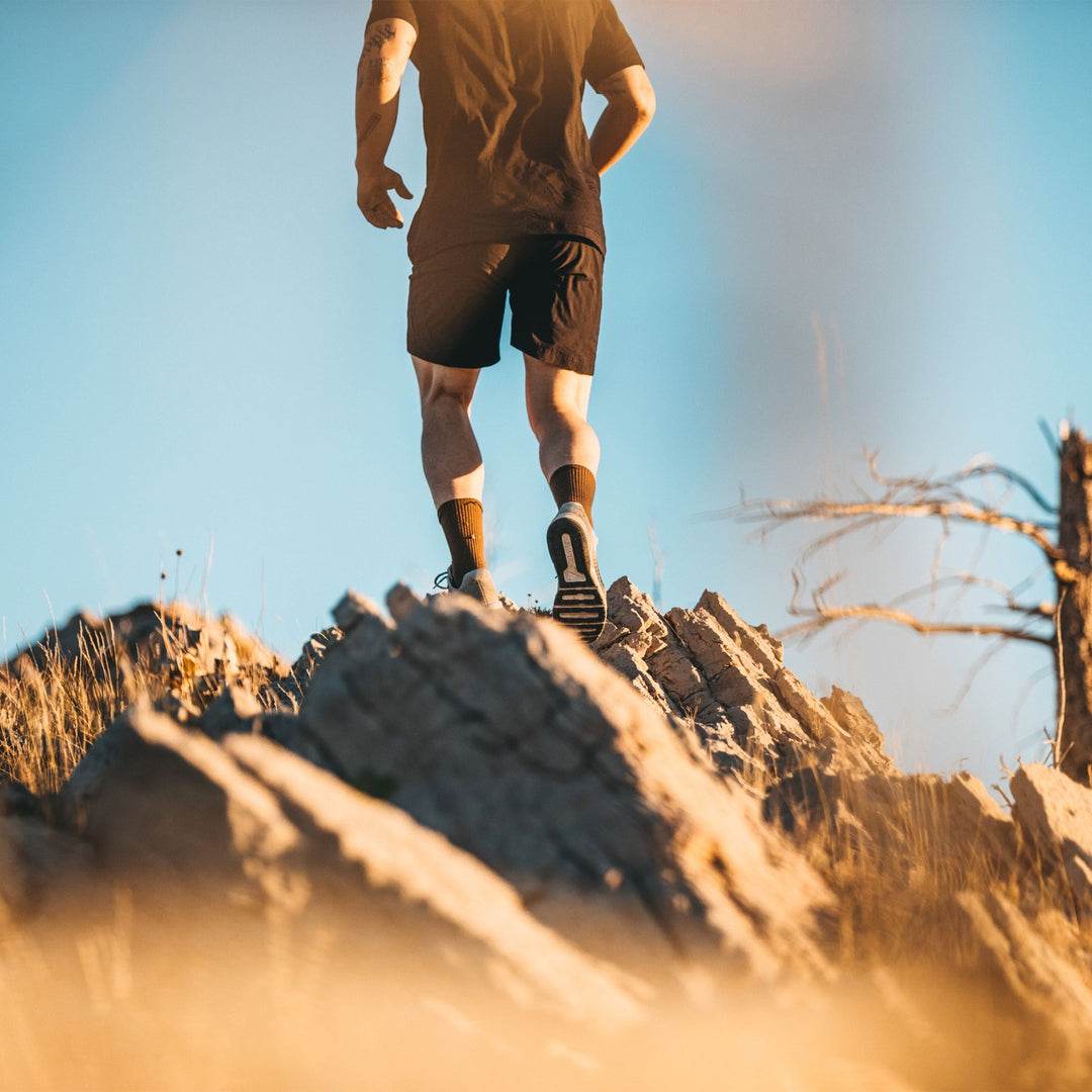 Man running on rocky terrain wearing Tactical Midweight Boot socks in coyote brown, Lifestyle Image