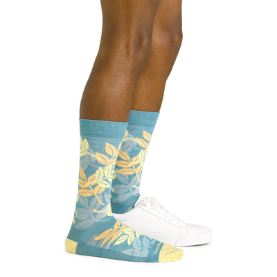 Side shot of model wearing the men's cabana crew lifestyle socks in aqua with a white sneaker on hisi left foot