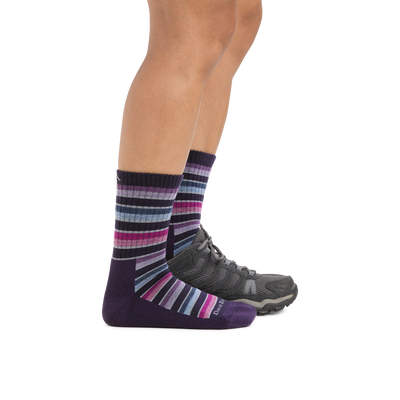 Profile image of a woman's legs on a white background, facing to the right, wearing Women's Decade Stripe Micro Crew Midweight Hiking Socks in Blackberry and the back foot also wearing a hiking shoe