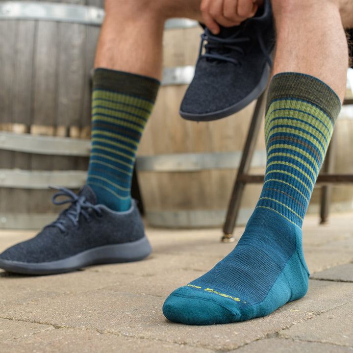 Close up shot of model sitting outside wearing the men's frequency crew lifestyle sock in dark teal