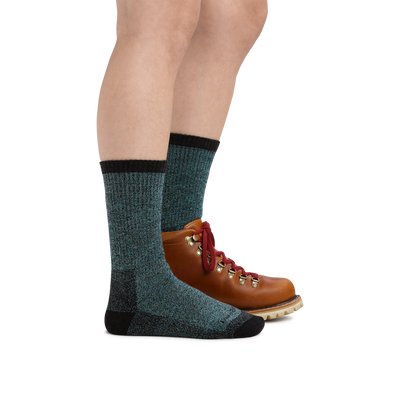 Profile image of a woman's legs on a white background wearing Women's Nomad Boot Midweight Hiking Socks in Aqua with one foot in a hiking boot
