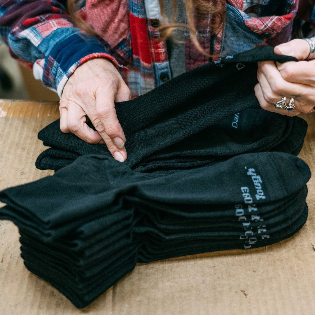 Overhead shot of employee in the nantanna mill packing large bundles of the T4093 quarter tactical sock in black