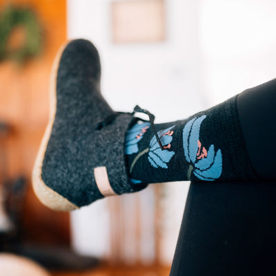 Close up shot of model laying down with her foot crossed in the air wearing women's lillies crew lifestyle sock in charcoal