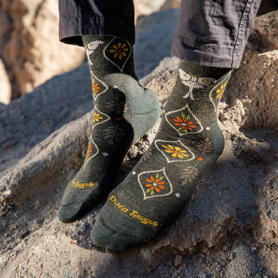 Close up of model wearing women's luna micro crew hiking sock in forest gray with rocks in the background