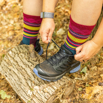Overhead shot of model tying their hiking boots wearing the women's ryder boot hiking socks in burgundy