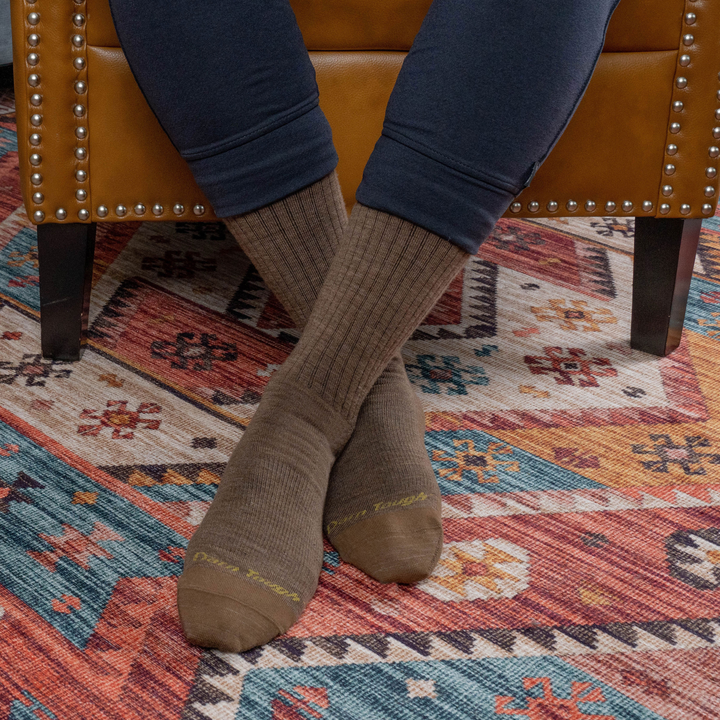 Close up shot of model sitting on a couch wearing the men's the standard crew lifestyle sock in bark